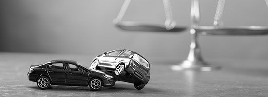 Mit Spielzeugautos symbolisierter Unfall vor einer Wage